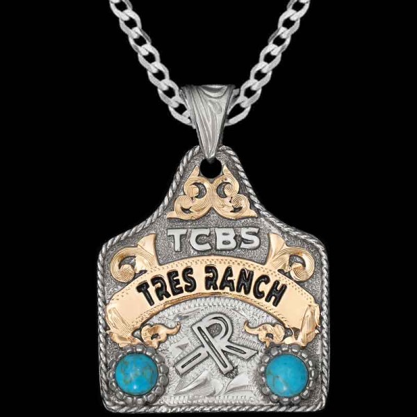 "Show off your Ranch pride with the Tux Cow Tag Necklace! Crafted on a hand-engraved, German Silver base with a natural finish. It's detailed with a German Silver rope edge, a Jeweler's Bronze banner and cubic zirconia stones with your choice of colo